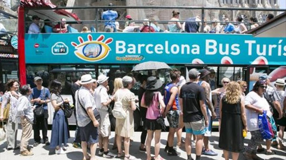 Unos visitantes hacen cola frente a la Sagrada Família para subir al Bus Turístic.