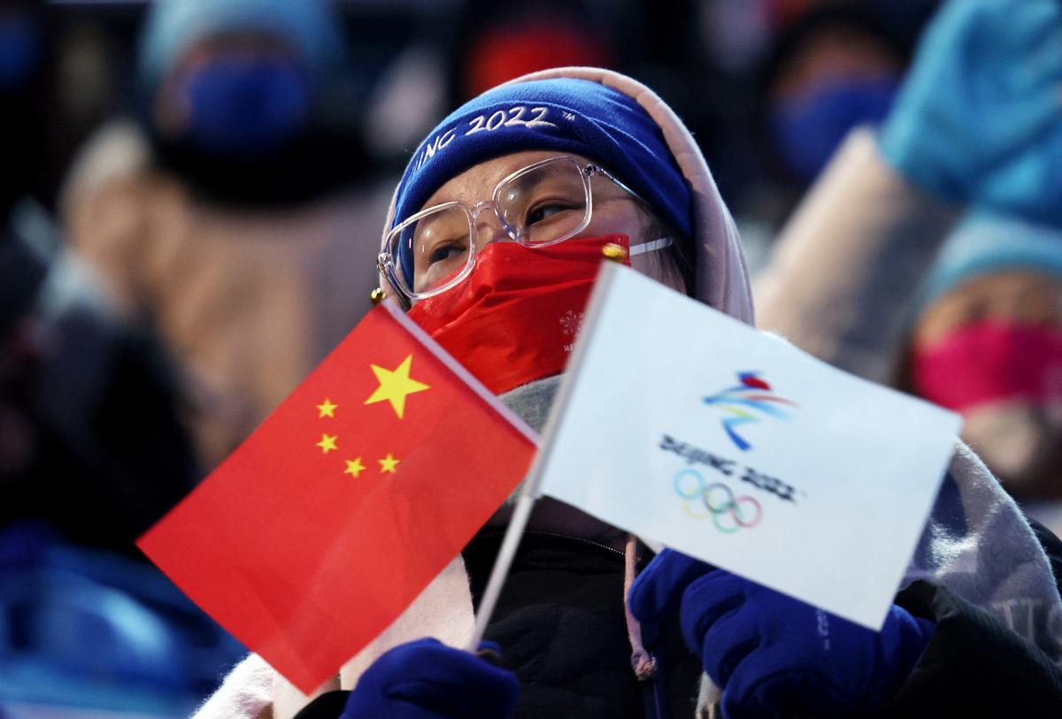 Un espectador que lleva una máscara sostiene una bandera nacional china y una bandera de Beijing 2022. REUTERS/Evelyn Hockstein