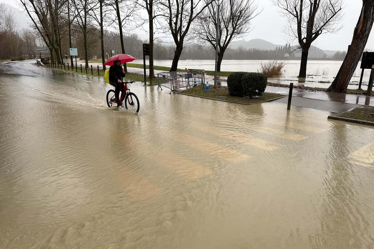 Un ciclista passant per una via amb aigua que ha sortit de l'estany.