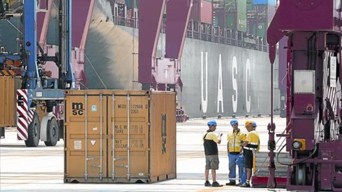 Trabajadores en los muelles del puerto de Barcelona, a punto para cargar un contenedor.