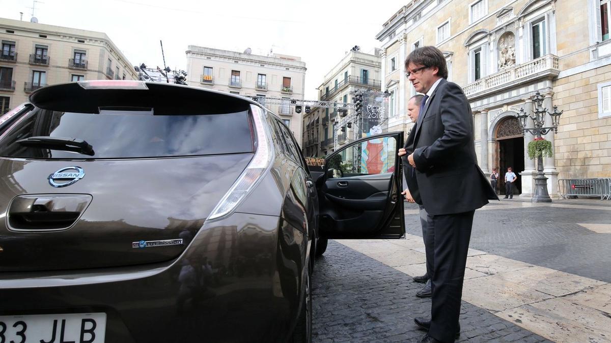 El 'president' de la Generalitat junto al coche eléctrico con el que se ha dirigido a la Generalitat