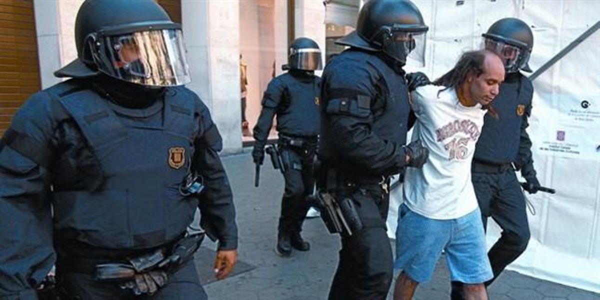 Dos mossos de la Brigada Mòbil condueixen un antisistema detingut al passeig de Gràcia durant els disturbis de dimecres passat.