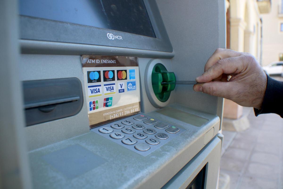 Una persona introdueix una targeta bancària a un caixer.