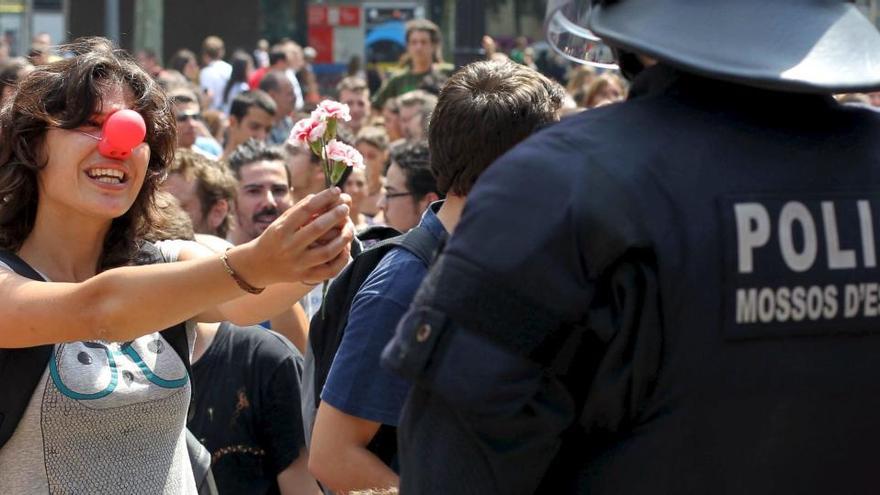 Una joven sostiene un clavel delante de un agente de los Mossos d&#039;Esquadra.