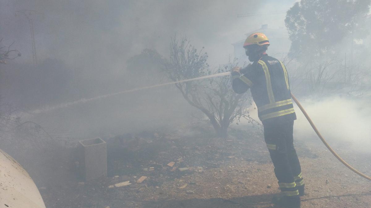 Un bombero apaga las llamas envuelto en la densa humareda