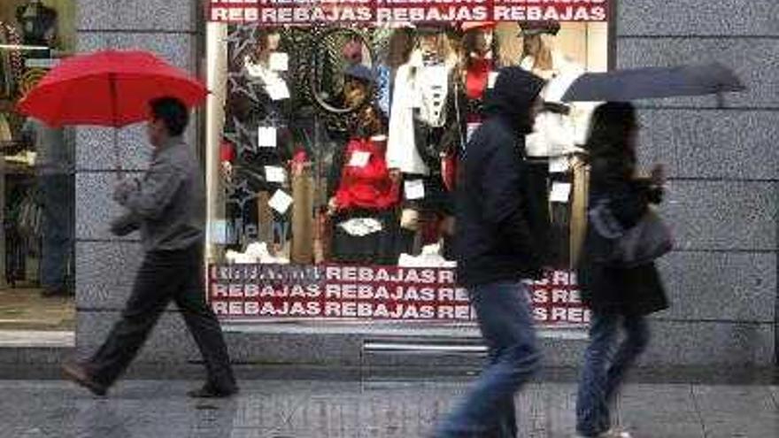 Menos existencias en prendas de abrigo, contención en el gasto y en el crecimiento de las ventas con respecto al año anterior protagonizarán, según consumidores y comerciantes, el primero y más importante periodo de rebajas del año que comienza mañana en la mayoría de comunidades autónomas. En la fotografía de archivo, tomada el 2 de enero de 2008, un comercio anuncia sus rebajas.