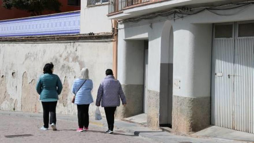 Tres veïnes caminen per davant la porta de l&#039;edifici de familiars de Manela Quesada.