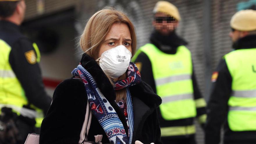 Una mujer camina con una mascarilla junto a miembros de la UME.