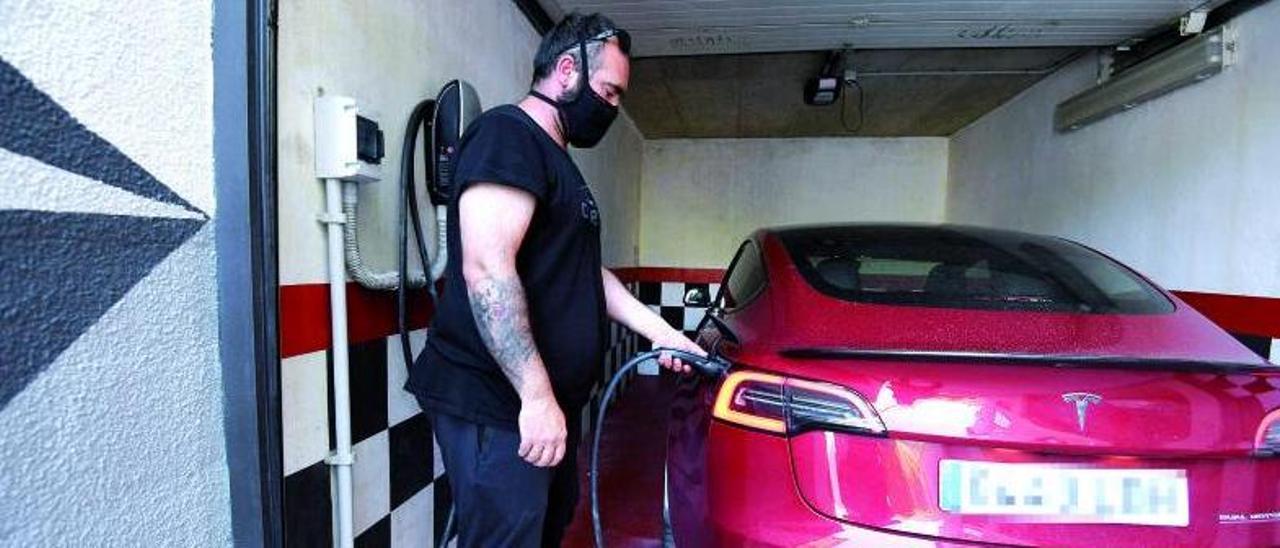Un hombre recarga su coche eléctrico en una plaza de garaje.