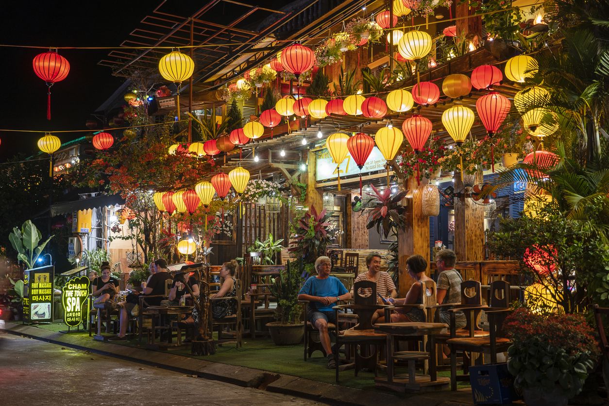 La gente descansa en un colorido restaurante cerca del río en la ciudad de Hoi An. Vietnam