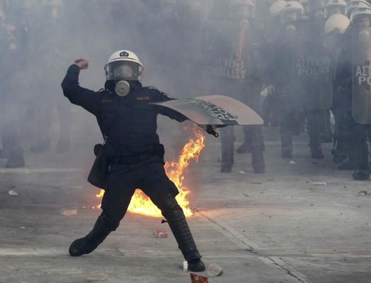 Un policia llança un objecte contra els manifestants davant el Parlament.