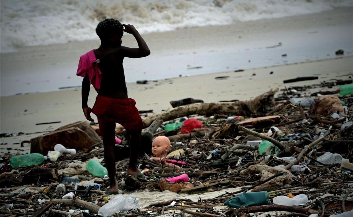 Un niño camina entre la basura que fue arrastrada por una tormenta en la playa de Sao Conrado este jueves, en Río de Janeiro (Brasil). Al menos cinco personas murieron y otras más están desaparecidas debido a la tempestad de lluvia y viento que arreció durante la noche del miércoles en la ciudad de Río de Janeiro, declarada en estado de emergencia tras el fuerte temporal.