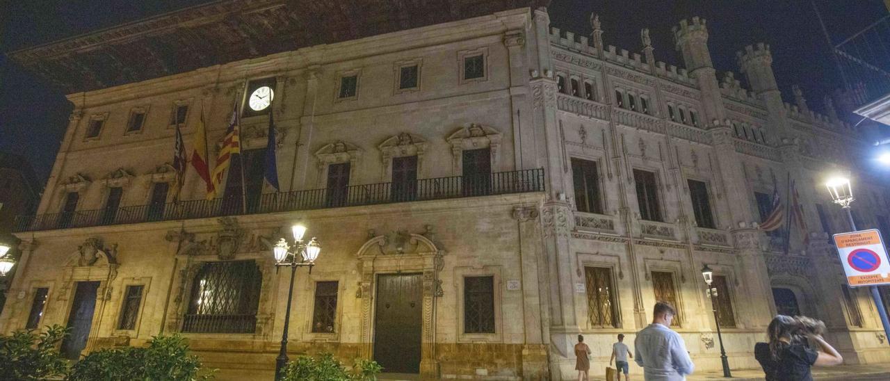 A la izquierda, el ayuntamiento de Palma ayer con las luces, ahora sí, apagadas. A la derecha, la fachada del Consell de Mallorca, que sí las apagó el primer día. | G.BOSCH