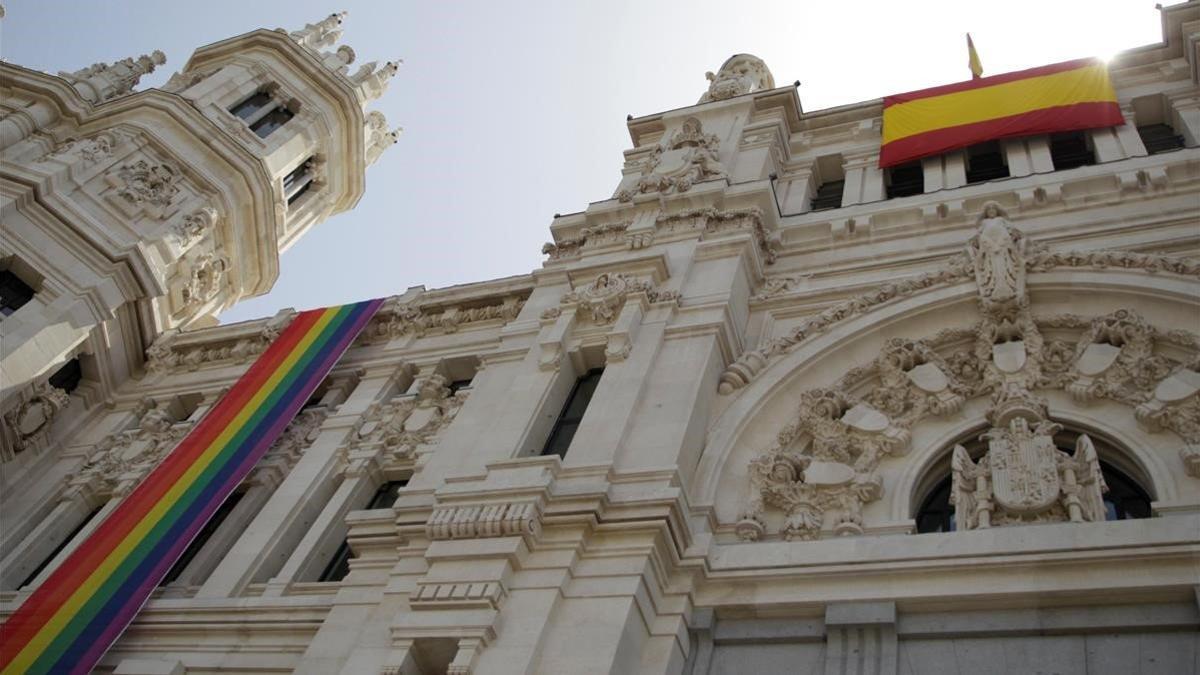 La bandera arcoíris del colectivo LGTBI, instalada en la fachada del Ayuntamiento de Madrid junto a una bandera de España