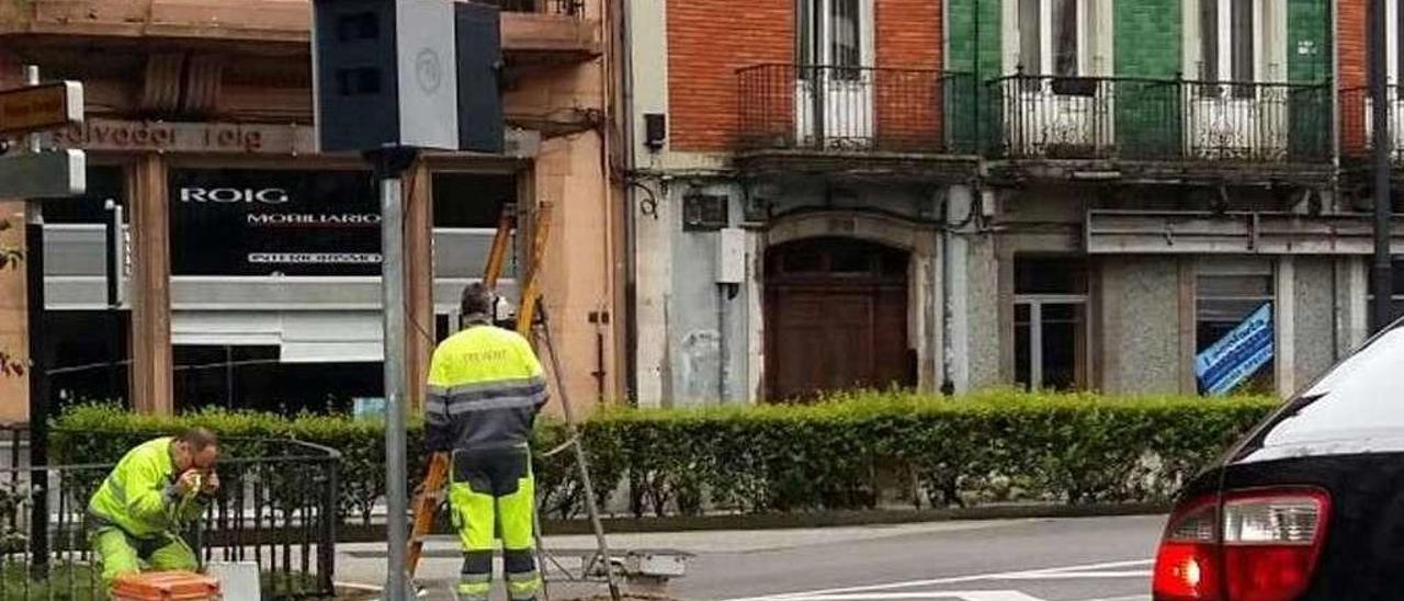 Dos operarios del Ayuntamiento colocan el radar de la avenida de Santander después de que fuera derribado, en abril de 2016.