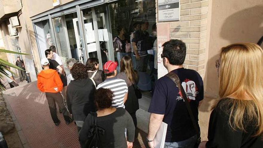 Un grupo de alicantinos hacen cola ante las puertas del Inem.