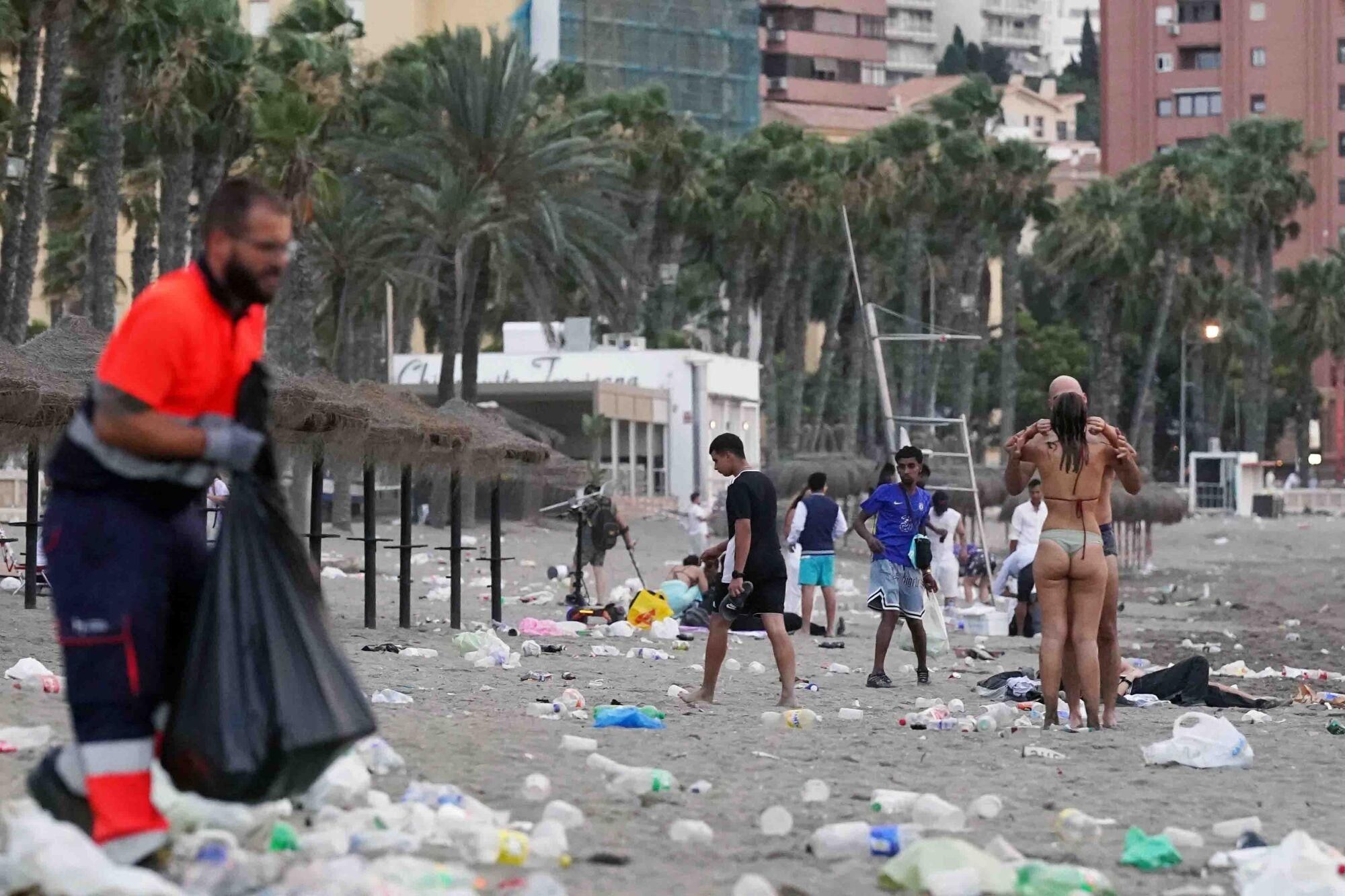 Varios operarios de la empresa de limpieza de Limasam, recogen los residuos de la playa de La Malagueta, tras la Noche de San Juan en Málaga 2025