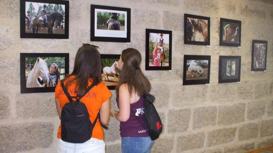 Dos jóvenes observan las fotografías de la exposición que se puede visitar en la Oficina de Turismo. Foto