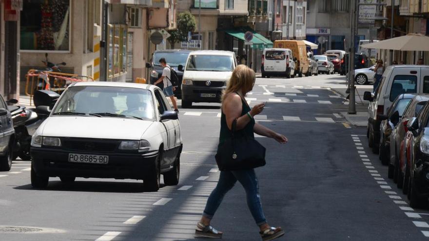 Una mujer cruza una calle de Cangas.