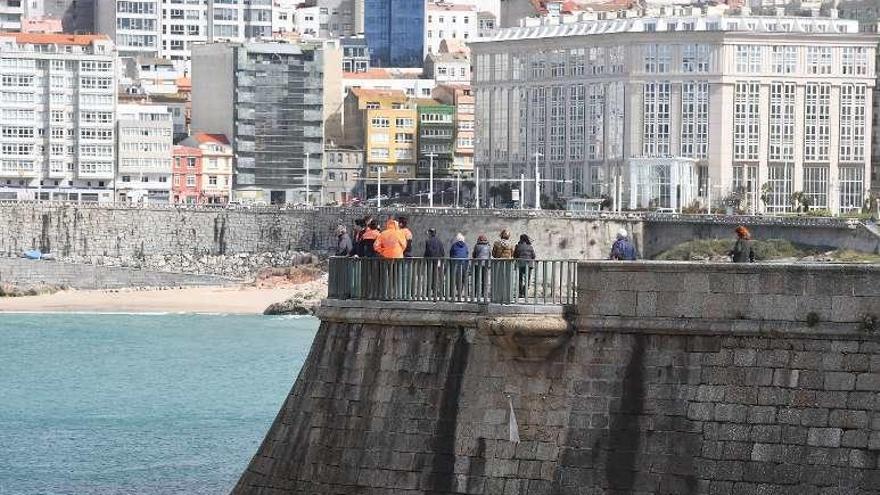 Un grupo observa el estado del mar ayer en A Coruña.