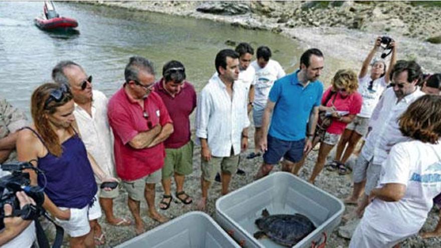 Bauzá (con polo azul) junto al conseller Company, y al fondo las lanchas que usaron en Cabrera.