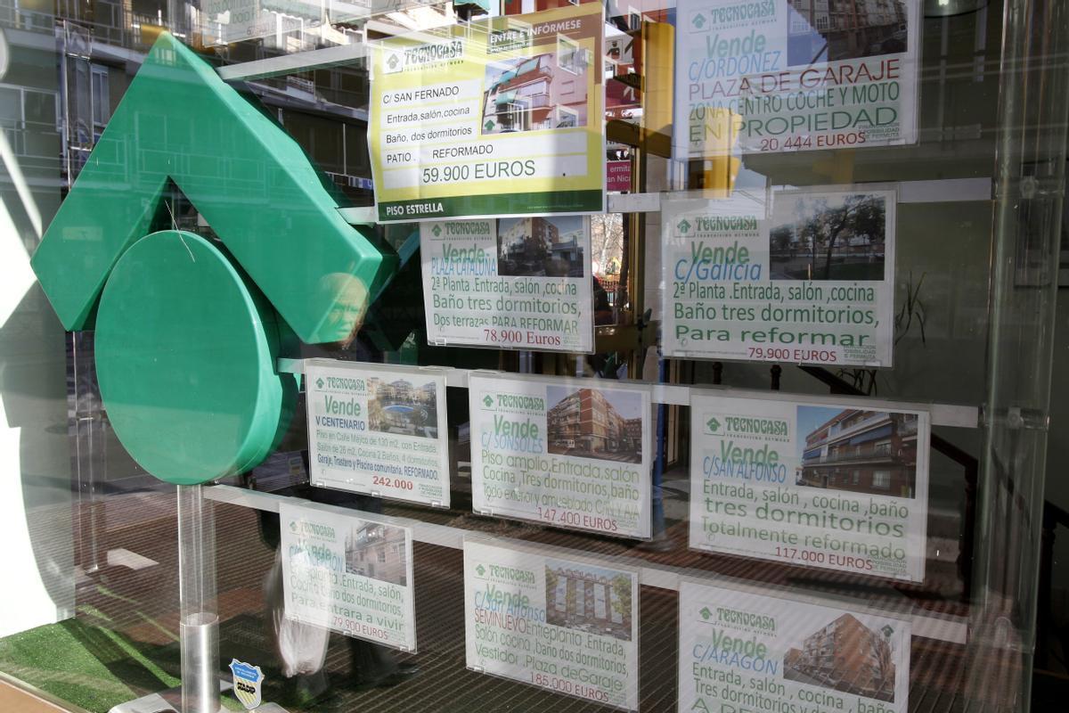 Imagen de archivo de carteles de venta de pisos en el escaparate de una entidad inmobiliaria.