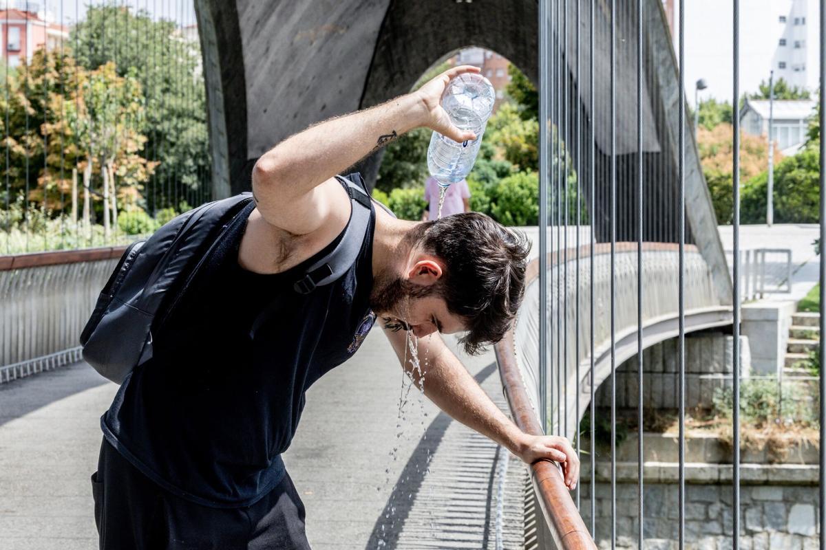 Un chico se moja la cabeza para combatir el calor en Madrid.