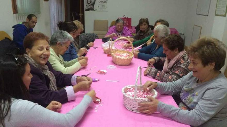 Las mujeres de la AECC elaboran lazos rosas que repartirán hoy por las calles.