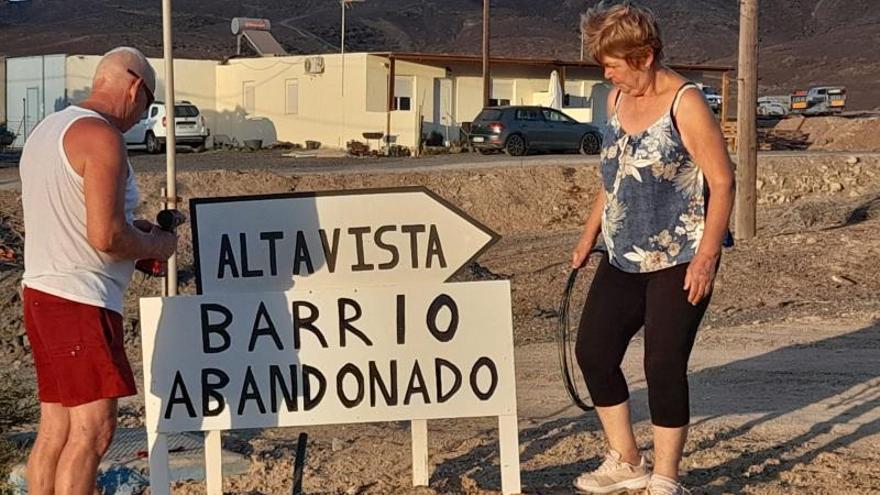 Dos vecinos colocando un cartel a la entrada del barrio.