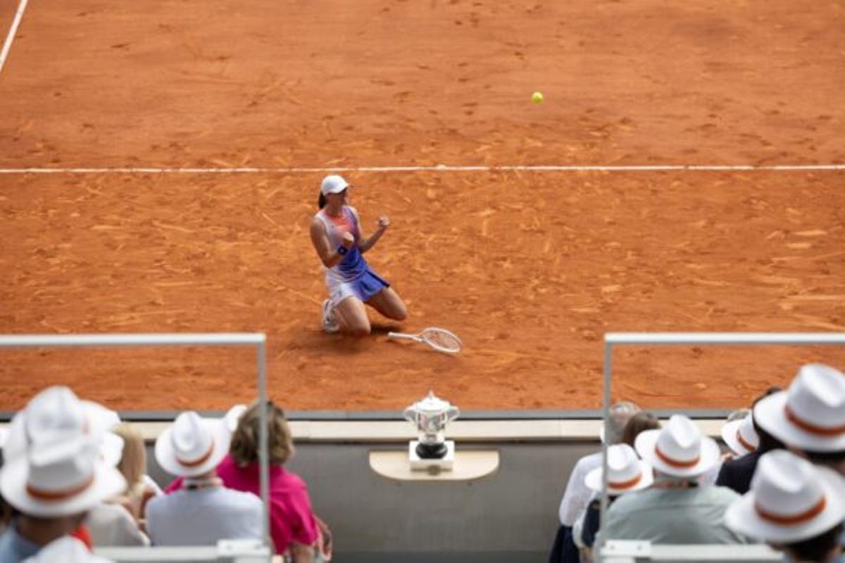 Iga Swiatek cae de rodillas en señal de celebración tras ganar el título individual femenino de Roland Garros 2024 en junio.