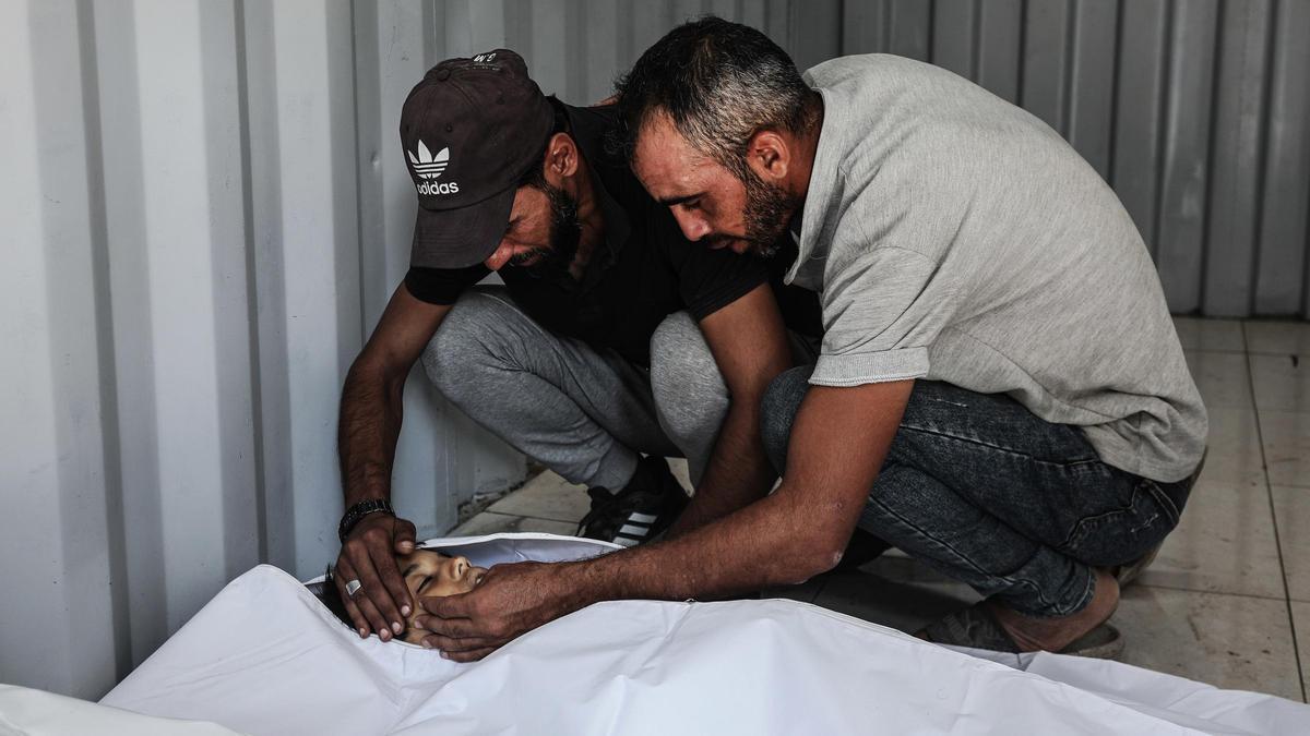 Palestinos en el Hospital Al Auda del campamento de refugiados de Nuseirat junto a un muerto por los ataques del Ejército de Israel contra la Franja de Gaza.