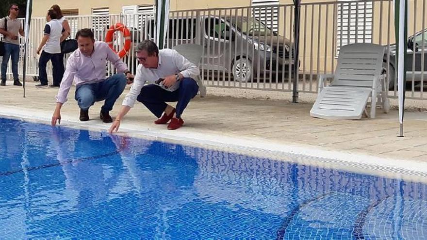 El alcalde (i) toca el agua de la nueva piscina del albergue de La Culebrina, junto al edil de Turismo, Francisco Montiel.