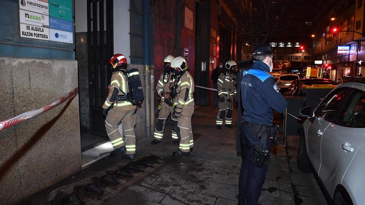 Bomberos y Policía Local ante el portal donde se produjo el incendio.