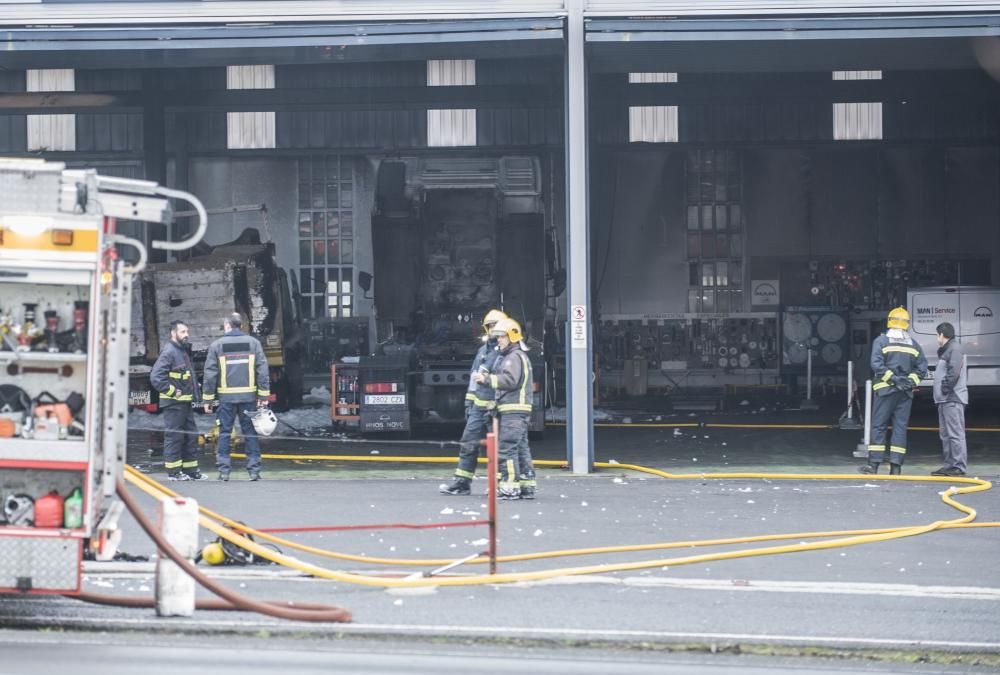 Bomberos del parque comarcal y efectivos de emergencias de Oleiros apagan un fuego en una nave de la compañía MAN situada junto a la Nacional VI - El fuego calcinó un camión y afectó a otros dos.