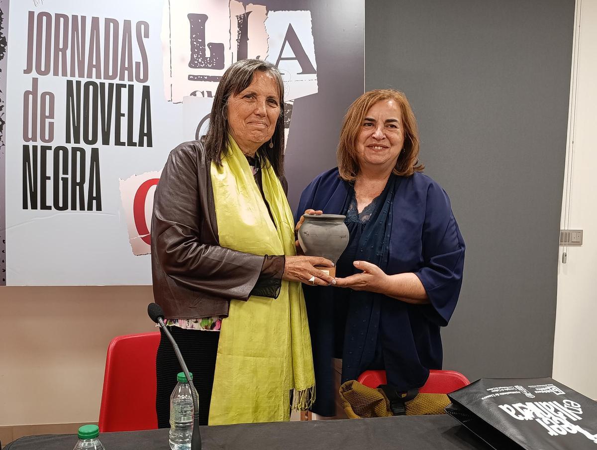Por la izquierda, Claudia Piñeiro recibe de manos de Montse Alonso una réplica de una olla votiva.