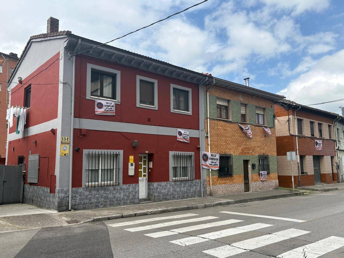 Viviendas de la calle José Álvarez Valdéz, en el barrio de El Puente, con pancartas contra las expropiaciones