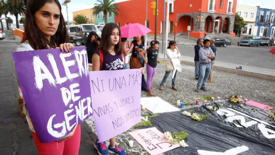 Dos mujeres muestran carteles de repulsa por el asesinato durante una manifestación en Puebla.