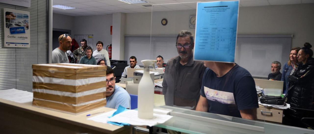 El patrón mayor de Cangas, Javier Costa, al fondo de pie en las votaciones de ayer en la lonja. |   // G.N.