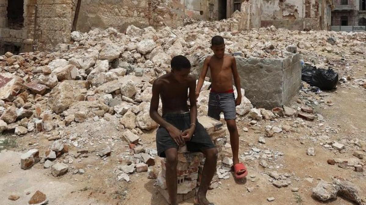 Dos joves descansen entre maons i cases enderrocades, a l’Havana. | ERNESTO MASTRASCUSA / EFE