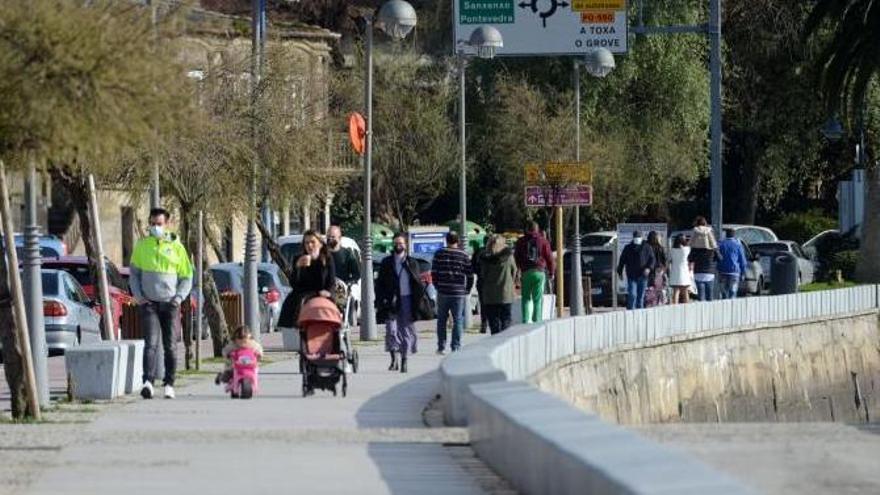 Vecinos caminan por el paseo marítimo de Cambados