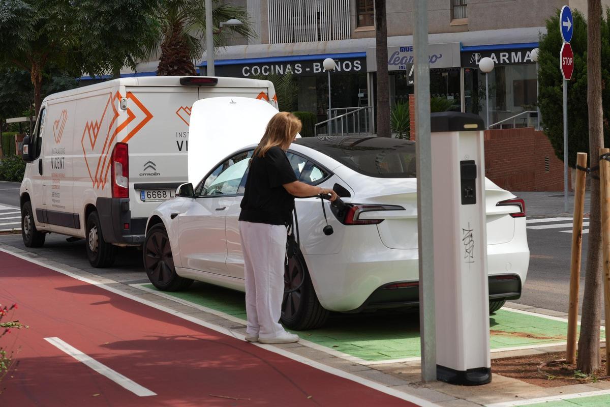 Una mujer utiliza un punto de recarga de un vehículo eléctrico en una calle de Castelló.