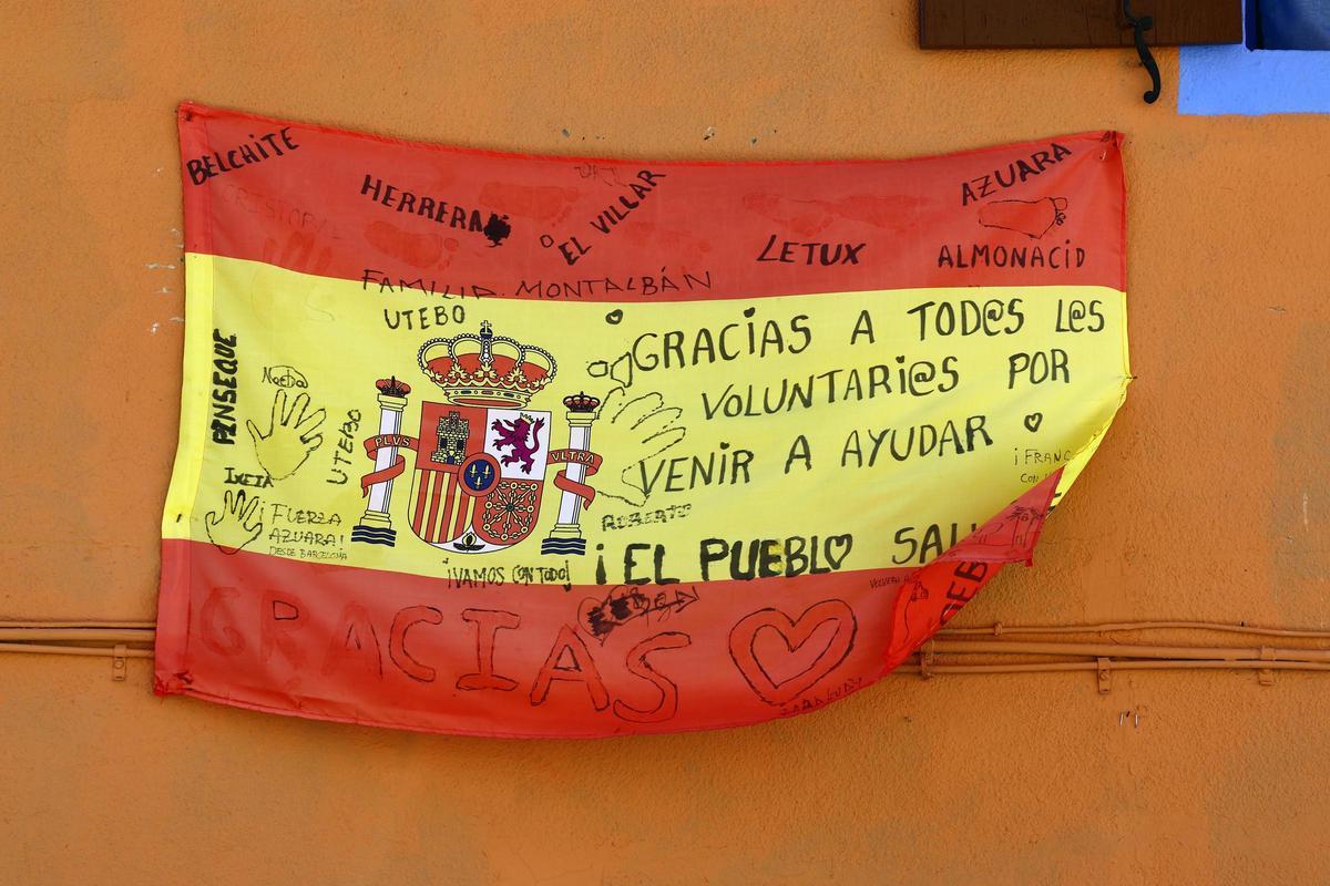 Firmas de agradecimiento a los voluntariossobre una bandera de España.