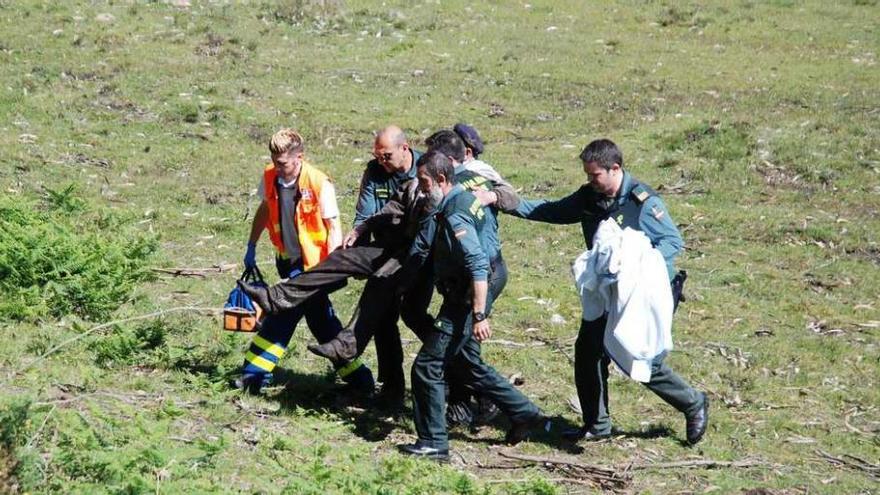 Guardias y un técnico sanitario trasladan al hombre hacia un todoterreno para acercarlo a la ambulancia.