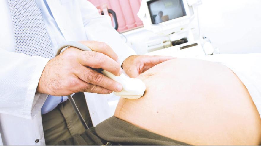 Un profesional sanitario realizando una ecografía a una mujer embarazada.