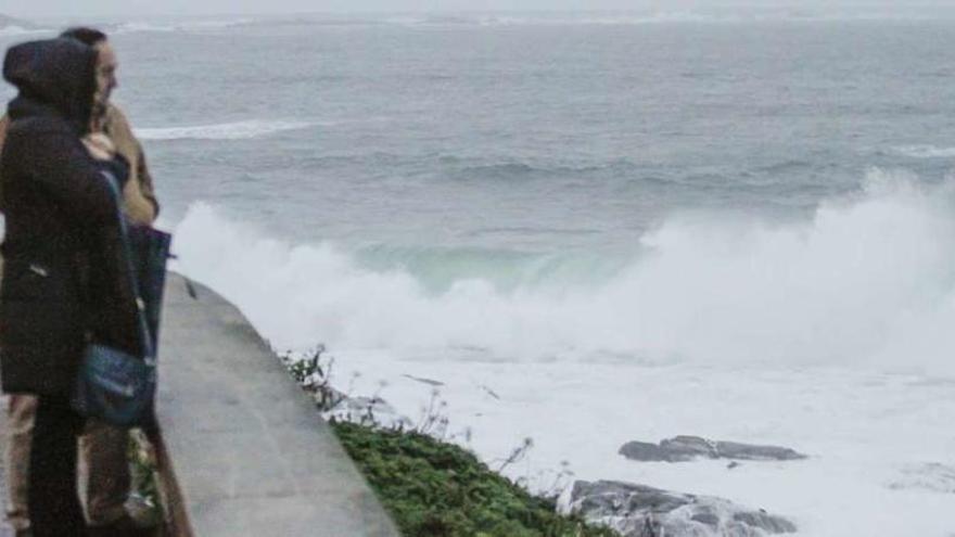 Dos personas contemplan el temporal en el mar en las inmediaciones de Baiona. // Adrián Irago