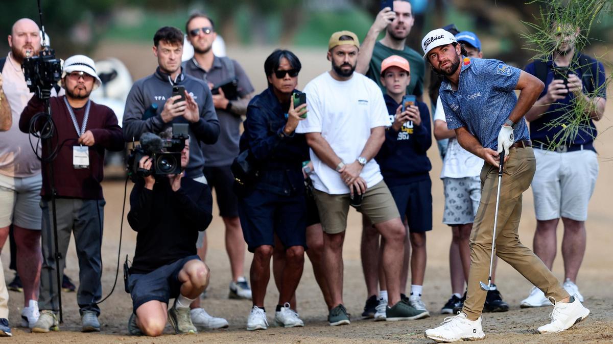 Cameron Young observa su bola tras el golpe ante la mirada de aficionados y cámaras en Dubai