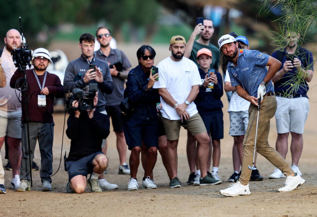 Cameron Young observa su bola tras el golpe ante la mirada de aficionados y cámaras en Dubai