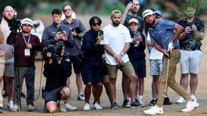 Cameron Young observa su bola tras el golpe ante la mirada de aficionados y cámaras en Dubai