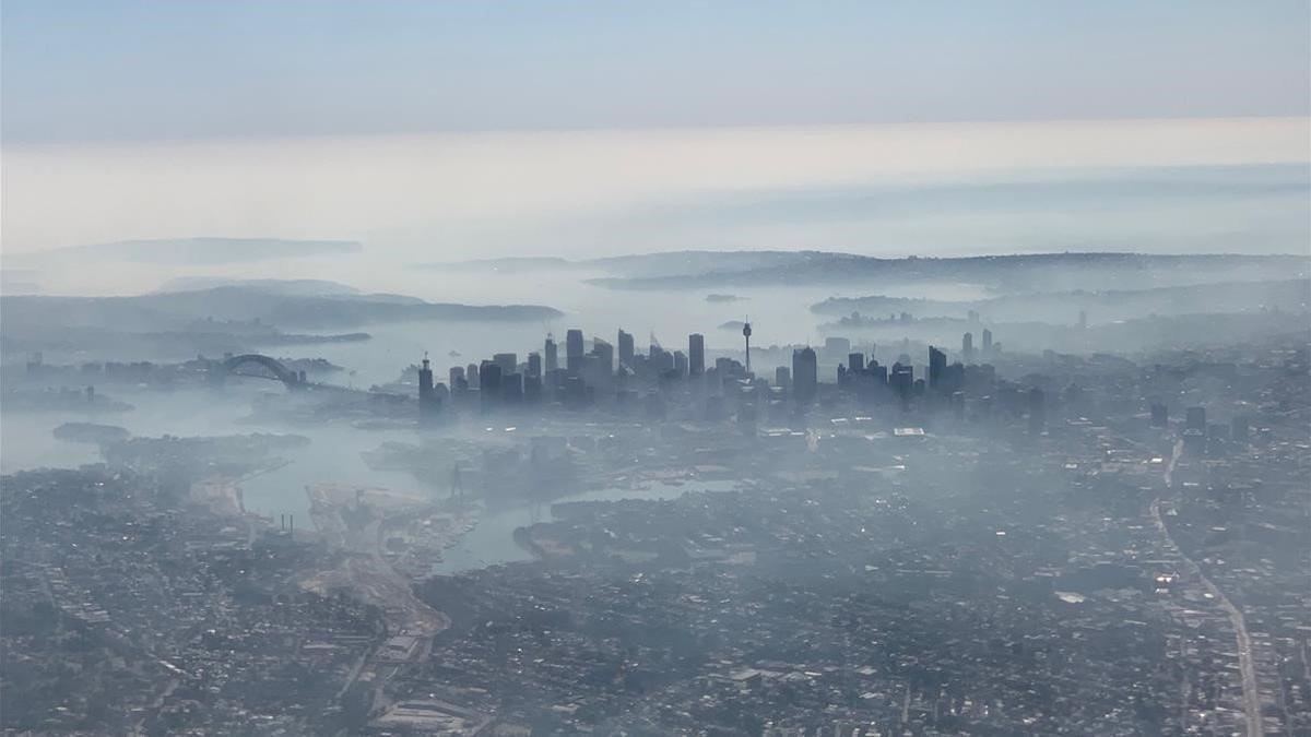 Imagen aérea de la ciudad de Sídney cubierta por una densa nube de humo blanco, este martes.