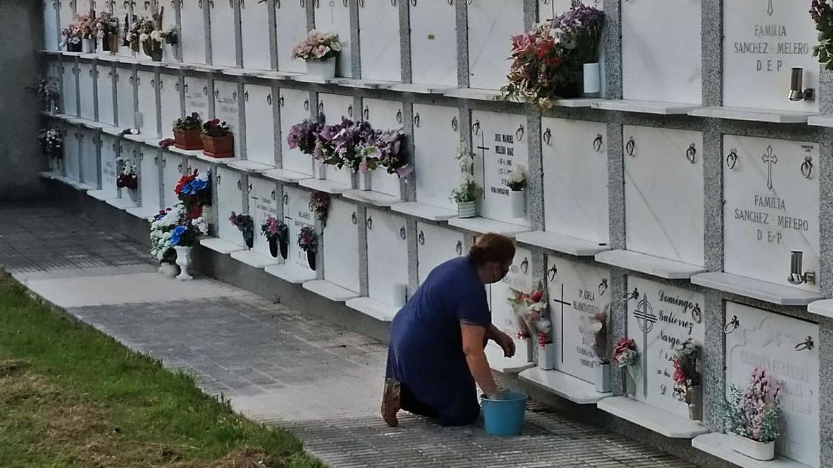 María Ángeles Noriega limpia el nicho de sus padres en el cementerio de Panes. | Eva San Román